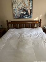 Wood bed frame with detailed headboard shown with white bedding, no decor items on headboard.