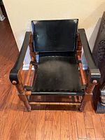 Front view of chair showing black leather seat and back on turned wood frame