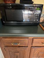 Full view of black Hamilton Beach microwave oven on kitchen counter with control panel visible.