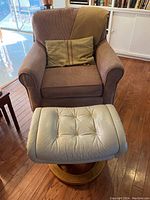 Photo showing the oversized chair with matching tufted leather ottoman on a wooden base