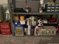 Photo of various paint supplies, mineral spirits, and household sprays stored on a concrete floor in front of a Craftsman toolbox/bench.