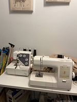 Front view of Kenmore sewing machine and serger on table with wall decorations in background