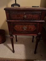 Front view of the antique side table showing both drawers and carved legs.