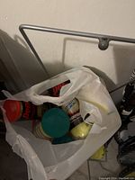 View into white plastic bag containing multiple cans of tennis balls and loose tennis balls.