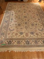 Full image of wool area rug showing design, colors, and scale on wooden floor