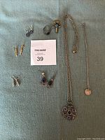 Full lot overview showing all items: 6 pairs of earrings, 2 necklaces, and 2 rings on a blue background