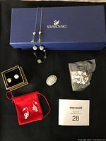 Necklace on top of Swarovski box, brooch, acrylic flower magnetic brooch in bag, kitten crystal dangling earrings in red pouch, faux crystal earrings in box, lot tag