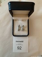Diamond cut silver earrings displayed in black jewelry box with cream interior, accompanied by MaxSold lot number card.