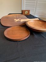 Photo showing the wooden bowl, tray, and charcuterie board with horse inset detail on a black surface
