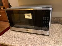 Stainless steel Panasonic microwave oven front view on countertop with door closed and price sticker.
