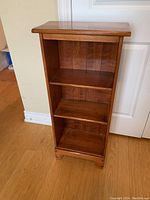 Front view of wooden shelf showing three fixed shelves against paneled back