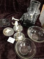 Full set of photo showing Cuisinart food processor base, bowl, lid, and multiple attachments including discs plus two clear Pyrex bowls.