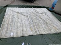 Full view of the light grey silk rug laid flat showing entire rug and general wear.