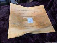 Top-down view of large square wooden bowl showing wood grain and natural finish.