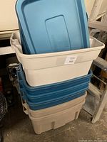 Stack of six Rubbermaid totes with beige and blue colors, blue lids shown on top without being sealed.