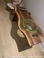 Side angled view of live edge walnut coffee table showing brass porthole and natural wood grain.