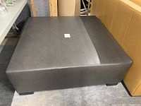 Top view of ottoman showing leather upholstery and oak legs