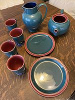 Full set including teapot, pitcher, tumblers, and plates arranged on wooden surface