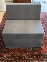 Front view of light blue/slate grey folding chair sleeper in chair position showing soft fabric cover and foam mattress seat.