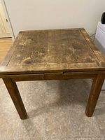 Top view of square oak table showing worn surface, scratches, and wood grain.