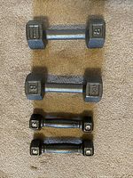 Top view of 2 eight-pound and 2 three-pound hex dumbbells laid out on carpet.