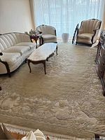 Full view of rug laid out in room under furniture, showing overall size, pattern and fringes visible at near end