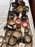 Photo showing multiple ladies belts in different colors and styles laid out on a bed.