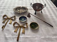 Top view of brass lot showing all items including bow hooks, ashtray, colander, candle snuffer, and trinket bowls.