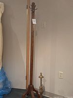 Full view of wooden coat rack standing next to the brass lamp base