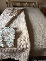 Queen size beige coverlet on bed with floral and cream striped coverlet layered on top