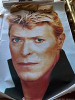 Close-up large portrait of David Bowie with light hair and blue eyes, worn edges