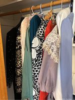 Dresses of various colors and styles hanging in closet including lace sleeved and patterned dresses