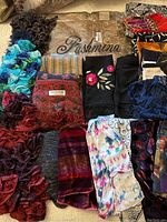 Photo showing collection of various scarves with knitted and woven textures in multiple colors.
