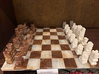 Full view of the marble chessboard with all pieces arranged in starting position showing brown and white squares and pieces.