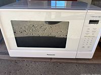 Front view of the white Panasonic Genius microwave showing door and brand name.