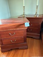 Pair of wooden nightstands showing front and side angles with scratches and brass handles.
