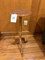 Full view of wooden pedestal stand showing round top, turned central column, and tripod legs.