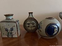 Photo showing all three pottery vases with different shapes and hand-painted designs.