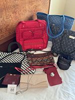 Full view of all purses, travel bags, and BLABOK travel pillow pouch arranged on bed.