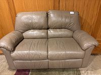 Front view of tan leather loveseat showing overall condition