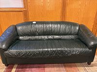 Front view of the dark green leather sofa showing full length and cushion design.