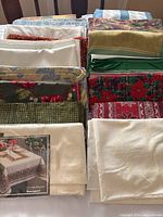 Overview of various folded tablecloths with different colors and holiday patterns