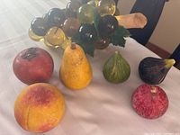 Full view of all stone fruit pieces and lucite grape cluster showing colors and arrangement on white surface