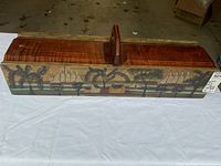 Full front view of antique wooden holder showing overall shape, handle, and scenic hand-painted design with sailboats, trees, and buildings.