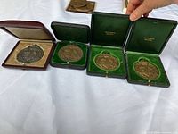 Four Do Right Medals displayed in three green and one maroon lined presentation cases, showing front views of medals with crests and text.