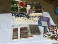Full overview of white wicker basket filled with pre-cut quilting fabric bundles and pattern packs