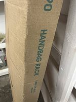 Side view of the cardboard packaging box labeled 'HAND BAG RACK',' showing the product name and model number.