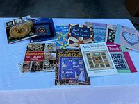 Photo shows a collection of quilting and needlecraft books spread on a table with visible titles and colorful quilt cover photos.