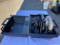 Sears Craftsman power circular saw placed inside open black plastic carrying case on white cloth outdoors.