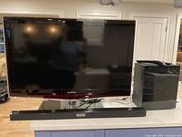 Samsung 40-inch LCD TV with wireless soundbar and subwoofer on a countertop.